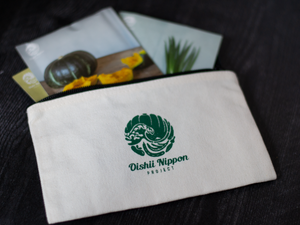 Canvas pouch with black zipper with dark green Oishii Nippon Project logo and words. 3 Oishii Nippon Project seed packets emerging from the pouch.